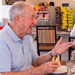 Senior man enjoying a meal and conversation in the Cafe at Fellowship Square Independent Living community